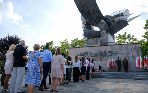 Ludzie i&nbsp;poczet sztandarowy składają kwiaty pod pomnikiem Bohaterskim Lotnikom Polskim.